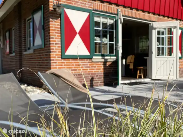 De openslaande tuindeuren bij de living komen uit op het terras aan de achterzijde.